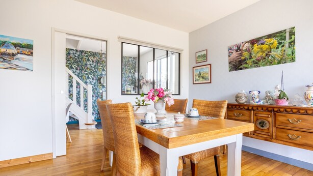 A dining area with a wooden table, wicker chairs, and a vase of flowers. - Ty Annick – Les Glénans Room (Névez)