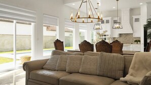 Un soggiorno moderno con un divano color beige, un lampadario e vista su piscina e giardino.