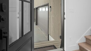 Un interior moderno con una puerta de vidrio de marco negro que da a un espacio interior de madera.