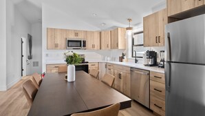 Una cocina moderna con armarios de madera, un refrigerador de acero inoxidable y una mesa de comedor con sillas.