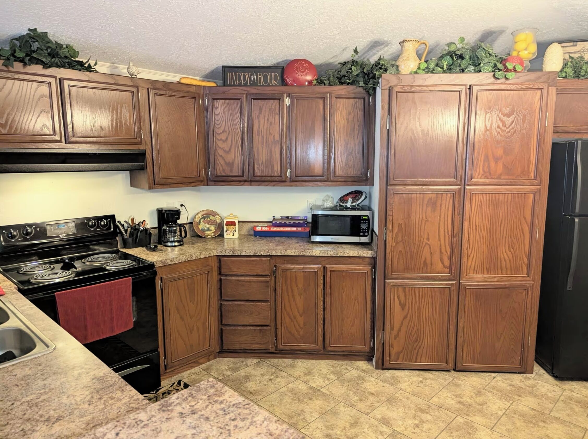 A kitchen with wooden cabinets, a stove, a microwave, and a refrigerator.