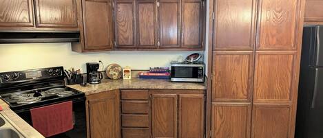 A kitchen with wooden cabinets, a stove, a microwave, and a refrigerator.