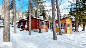 A cabin with a stone foundation and a wooden upper structure, surrounded by snow and trees. - Ely Lakeside Cabin: The Perfect Northwoods Retreat (Ely)