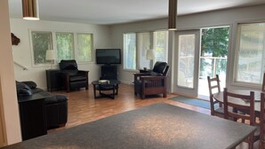 A living room with a fireplace, a TV, and a dining area with chairs. - Lakefront house with private dock (Lake Cowichan)