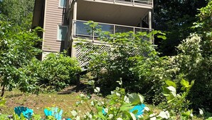 A two-story building with balconies, surrounded by dense greenery. - Lakefront house with private dock (Lake Cowichan)