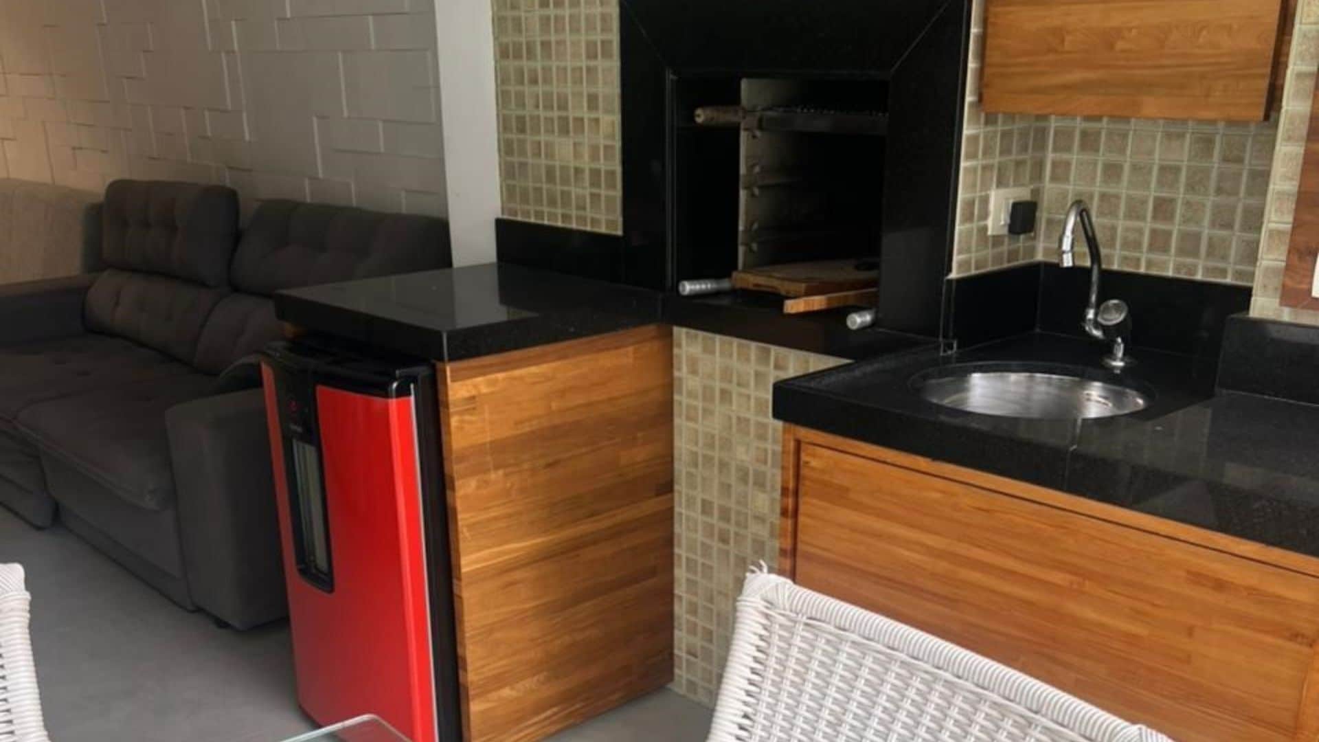 A compact kitchen with a black countertop, wooden cabinets, and a built-in sink.