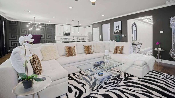 Un salon moderne avec un canapé blanc, une table basse en verre et un tapis à motifs zébrés.