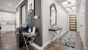 Une cuisine moderne avec des meubles blancs, un îlot central noir et un miroir décoratif.