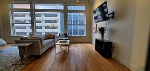 A modern living room with a sofa, coffee table, and TV mounted on the wall. - Studio Loft with King Bed Downtown (Dallas)