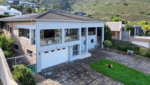 A modern two-story house with a garage, large windows, and a well-maintained lawn. - Family Suite - Indoor Hot Tub, Heated Pool, Play Park & Table Mountain Views (Cape Town)