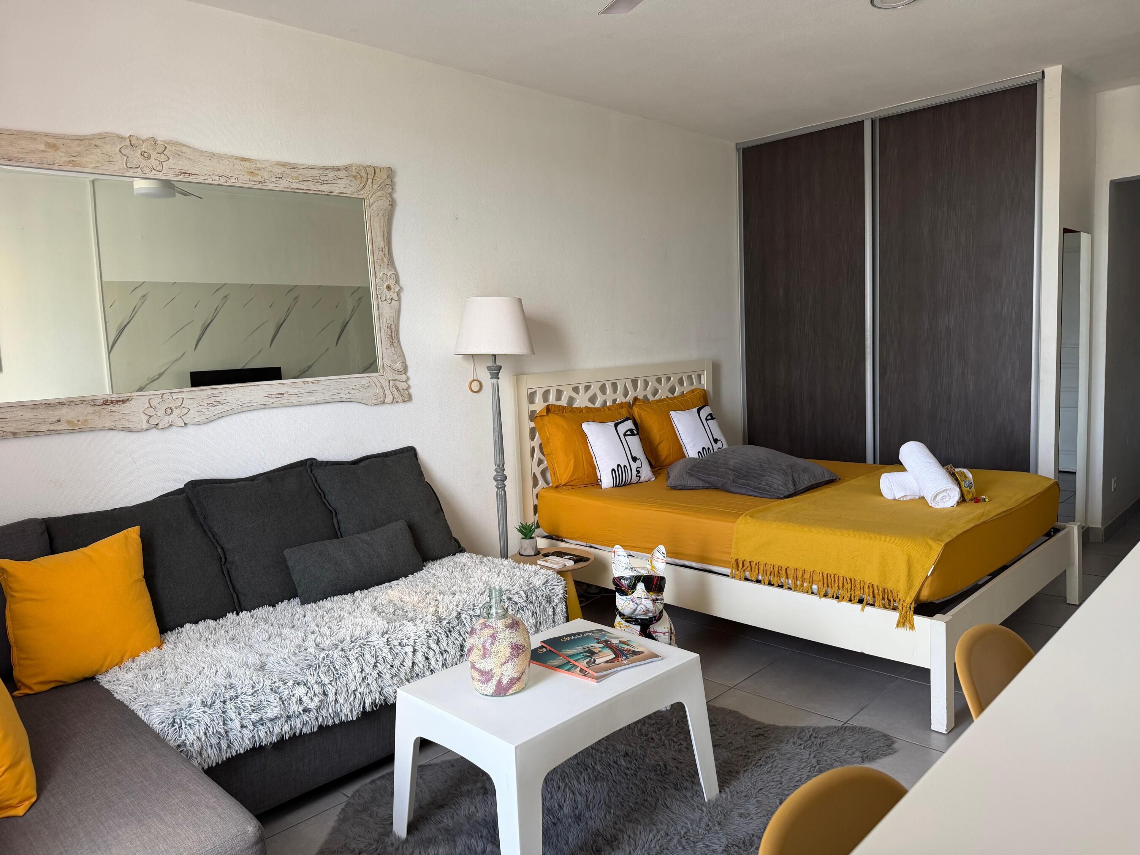 Ein modernes Hotelzimmer mit Bett, Sofa und kleinem Tisch.
