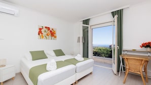 Une chambre d’hôtel avec un lit, un bureau et une vue sur la mer.