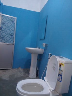 A bathroom with a toilet, a sink, and a door. -  Amaya Hotel and Restaurant (Dikwella)