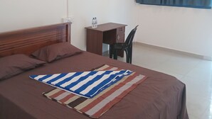 A bedroom with a bed, a desk, a chair, a ceiling fan, and a window with curtains. -  Amaya Hotel and Restaurant (Dikwella)