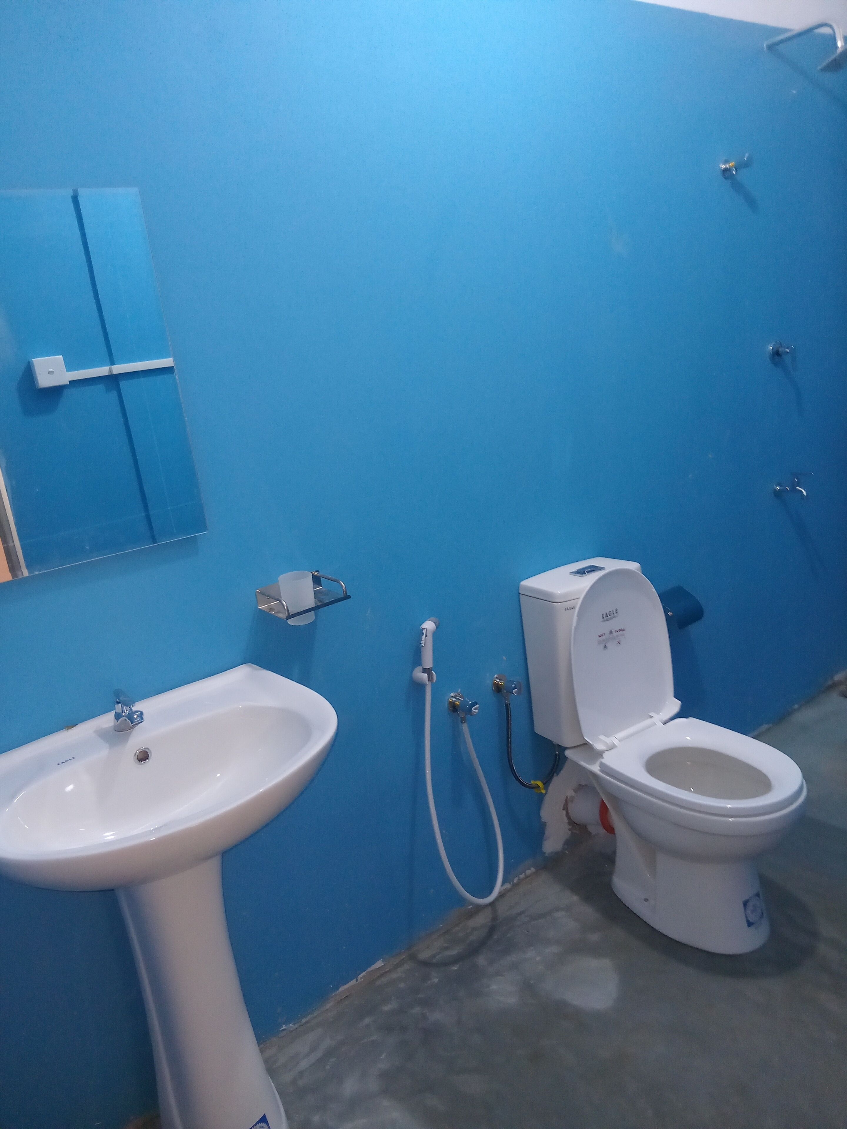 Un baño con un lavabo blanco, un inodoro y una pared azul.