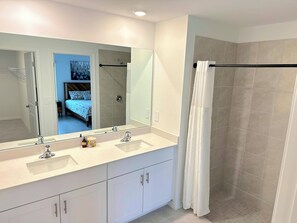A modern bathroom with a large mirror, two sinks, and a shower area. - Spacious, brand-new and modern 4-bedroom house in Paradise (Rotonda West)