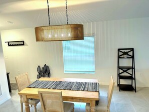 A dining area with a wooden table, woven placemat, and two chairs. - Spacious, brand-new and modern 4-bedroom house in Paradise (Rotonda West)