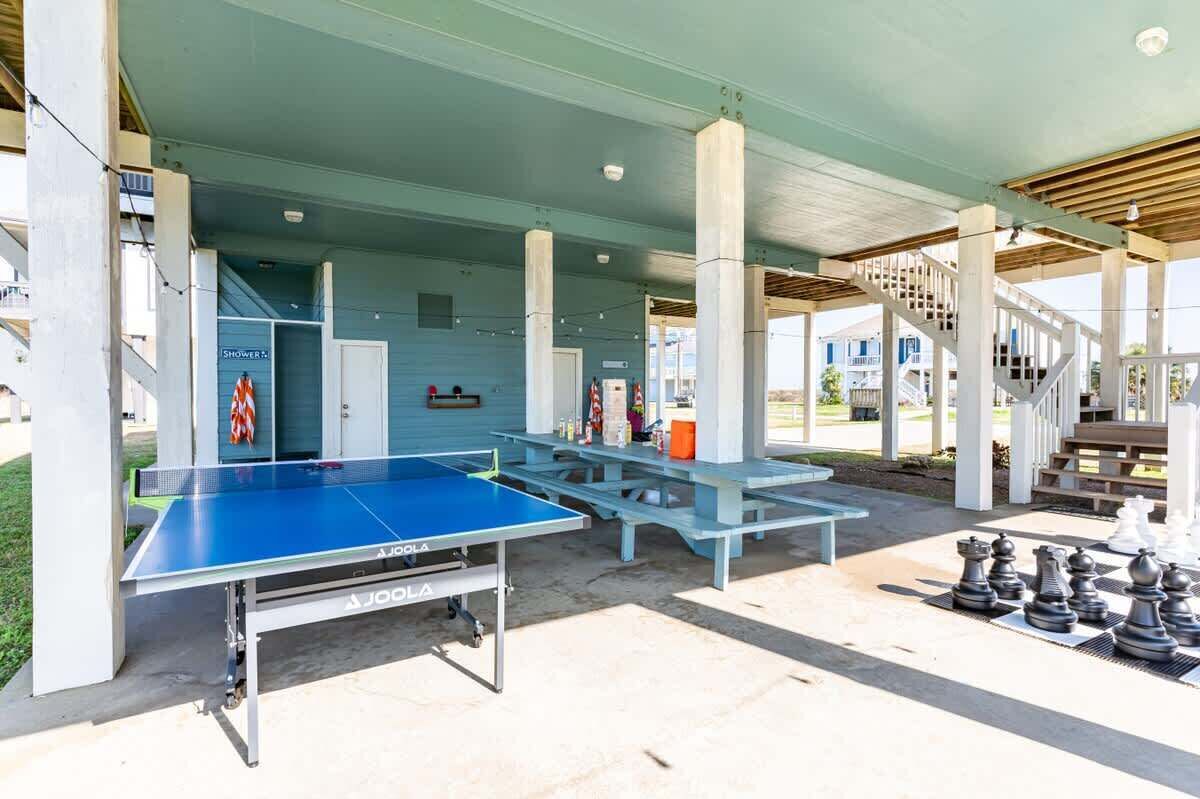 Een openluchtpaviljoen met een tafeltennistafel, picknicktafels en een schaakspel.