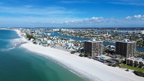 A coastal cityscape with a prominent beach, two high-rise buildings, and a marina. - Mansions By The Sea 905b - Premier (Treasure Island)