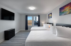 A hotel room with two beds, a flat-screen TV, a dresser, and a balcony with a view. - Stay In Our Winter Rental On MB Boardwalk (Myrtle Beach)