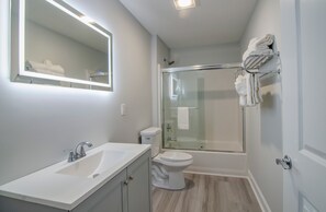A modern bathroom with a white sink, toilet, and glass-enclosed shower. - Stay In Our Winter Rental On MB Boardwalk (Myrtle Beach)