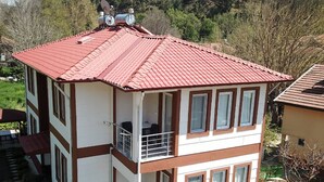 Ein zweistöckiges Gebäude mit roten Ziegeldach, zahlreichen Fenstern und einem Balkon.