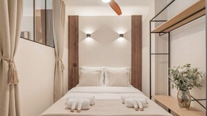 Ein modernes Hotelzimmer mit Bett, Nachttischen, einem Spiegel und einem Deckenventilator.