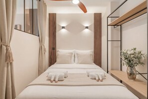 A modern hotel room with a bed, bedside tables, a mirror, and a ceiling fan. - Ideal Parisian apartment close to Montparnasse (Paris)