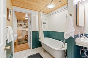 Een badkamer met bad, douche en wastafel.