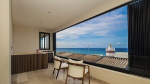 Een balkon met uitzicht op zee, een houten tafel, twee stoelen en een klein kastje.