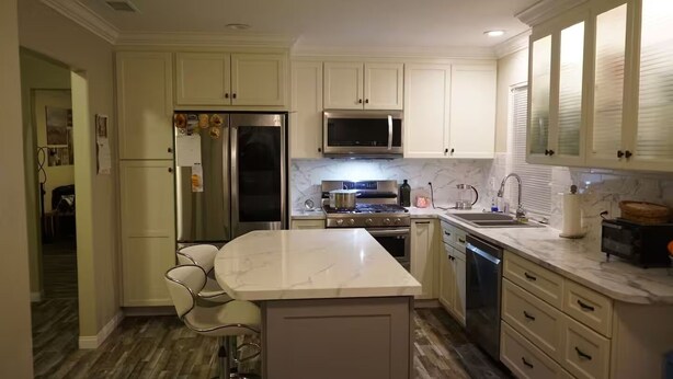 A kitchen with white cabinets, a stainless steel refrigerator, a microwave, a stove, and a dishwasher. - Terrific 3-bedroom house with AC in sunny Oceanside (Oceanside)