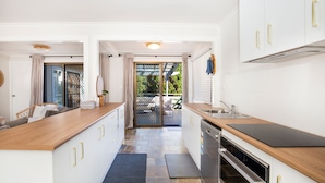 Une cuisine moderne avec des meubles blancs, un plan de travail en bois et un four encastré.