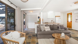 Un salon moderne avec un canapé, un fauteuil en osier et une table basse.