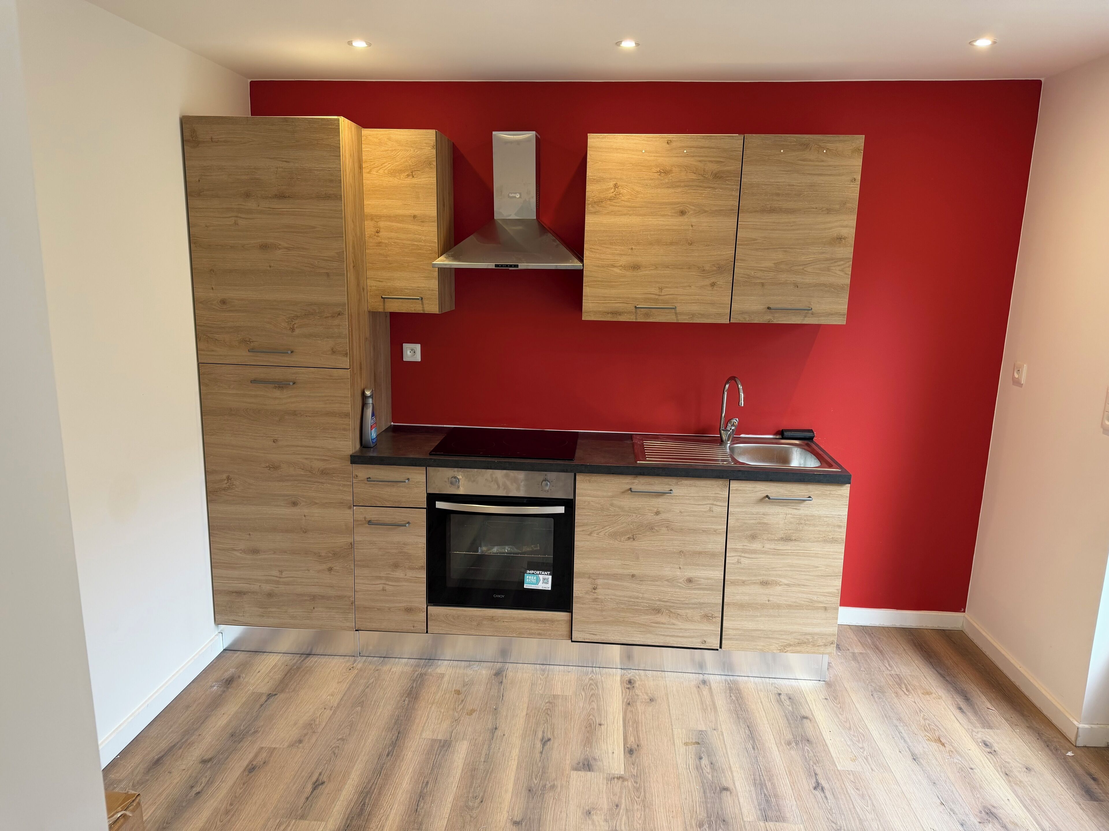 Una cocina compacta con gabinetes de madera, un lavamanos de acero inoxidable y un horno empotrado.
