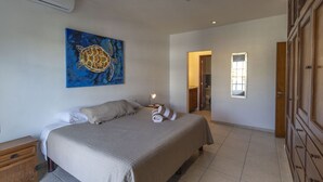 Ein Schlafzimmer mit einem Bett, einem Deckenventilator, einem Gemälde und einem Fenster.