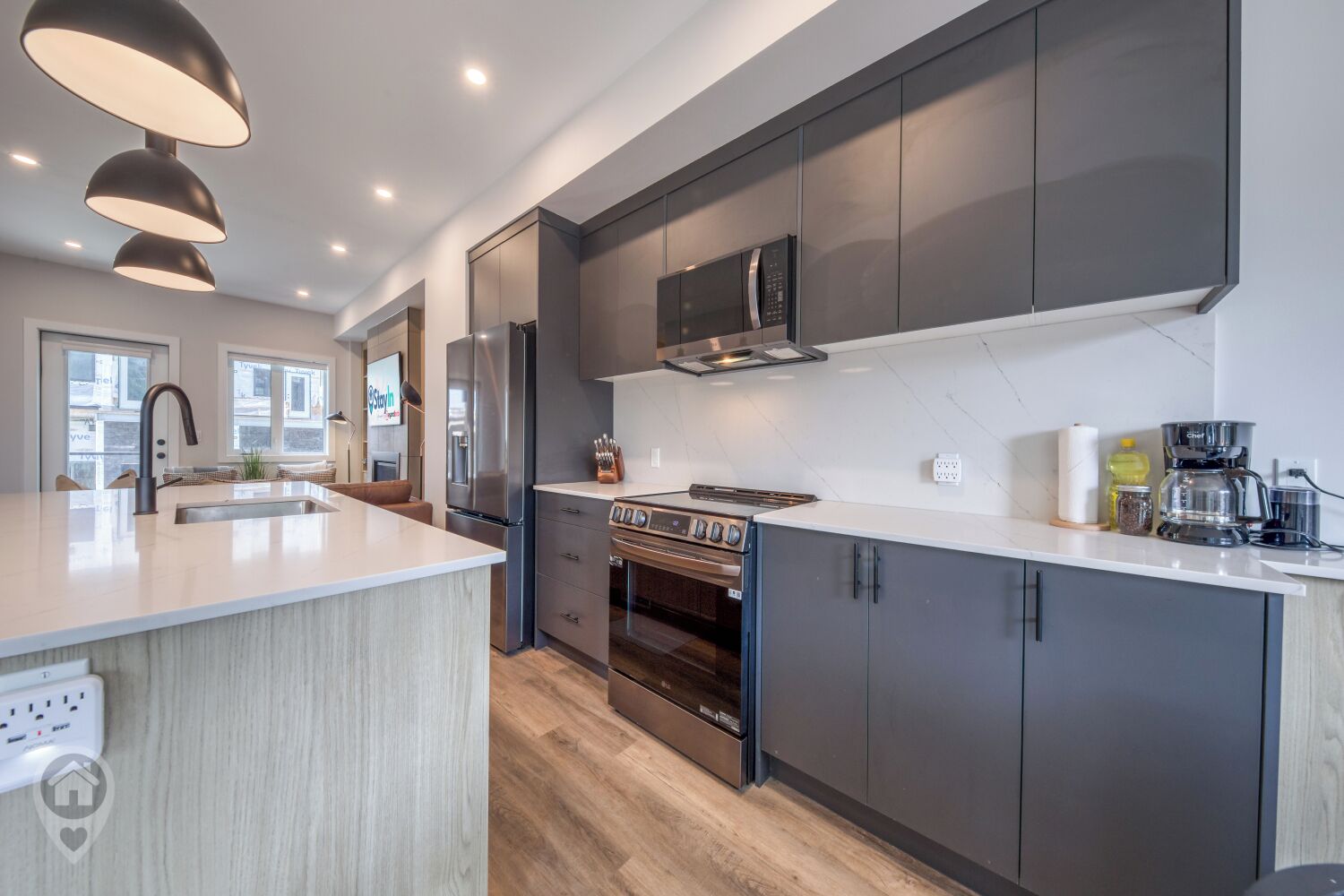 A modern kitchen with a central island, stainless steel appliances, and dark cabinetry.