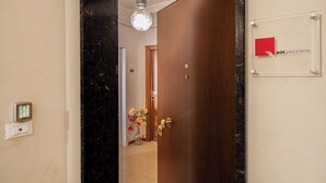 A hotel entrance with a marble wall, a wooden door, a security keypad, and a sign with 'pat pied à terre' text. - Pied à terre Relaxation. A spacious apartment in the historic center of Verona. (Verona)