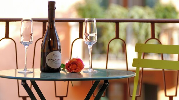 A table with a wine bottle, two glasses, and a rose. - Pied à terre Relaxation. A spacious apartment in the historic center of Verona. (Verona)