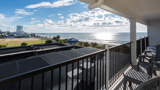 Een balkon met uitzicht op de oceaan en een reuzenrad in de verte.