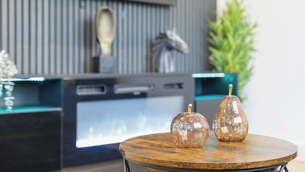 A modern interior with a round wooden table displaying two glass sculptures, a dark entertainment unit with a TV, and a green plant in the background. - Cozy  2-bedroom apartment in Canning Town near Excel London (London)