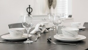 A dining table set with white marble bowls and wine glasses, a spoon, and a fork. - Cozy  2-bedroom apartment in Canning Town near Excel London (London)