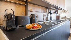 A modern kitchen with a black countertop, a coffee maker, a toaster, and a plate of croissants with strawberries.