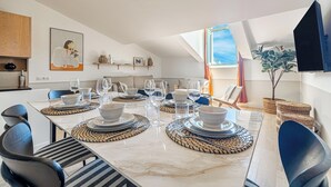 A modern dining area with a marble table set for six, surrounded by blue chairs.