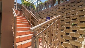 Eine Treppe mit Metallgeländer, die zu einem überdachten Bereich mit Glasdach führt.