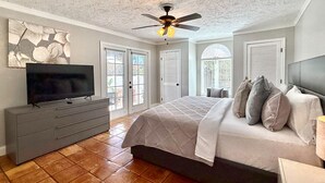 Ein Schlafzimmer mit Bett, Fernseher, Kommode und Deckenventilator.