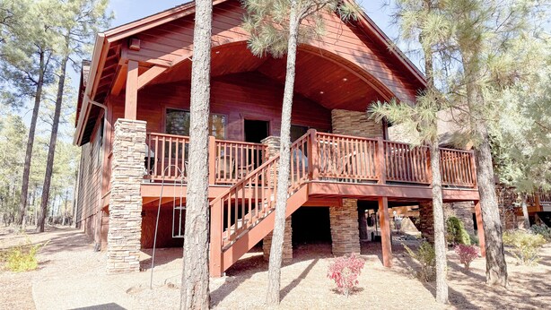 A wooden cabin with a balcony, stone pillars, and a stone foundation. - Bela's in Torreon with Golf Membership (Show Low)