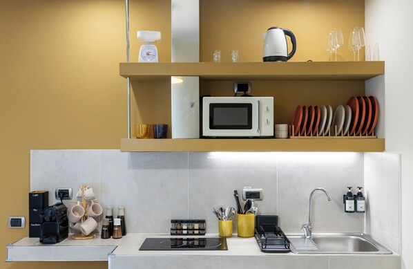 Una cocina moderna con microondas integrado, cafetera y pileta.