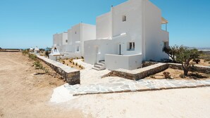 A modern white building with a stone pathway and a small tree in the foreground. - Villa THÉA II, Villa THÉA Naxos (Vivlos)