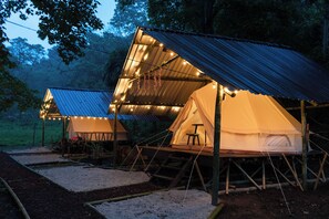 Two tents with attached wooden structures, each with a table and chairs, set in a forested area. - Aldea Alemm (Coatepec)