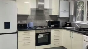 Een moderne keuken met een ingebouwde oven, een gasfornuis en een roestvrijstalen afzuigkap.